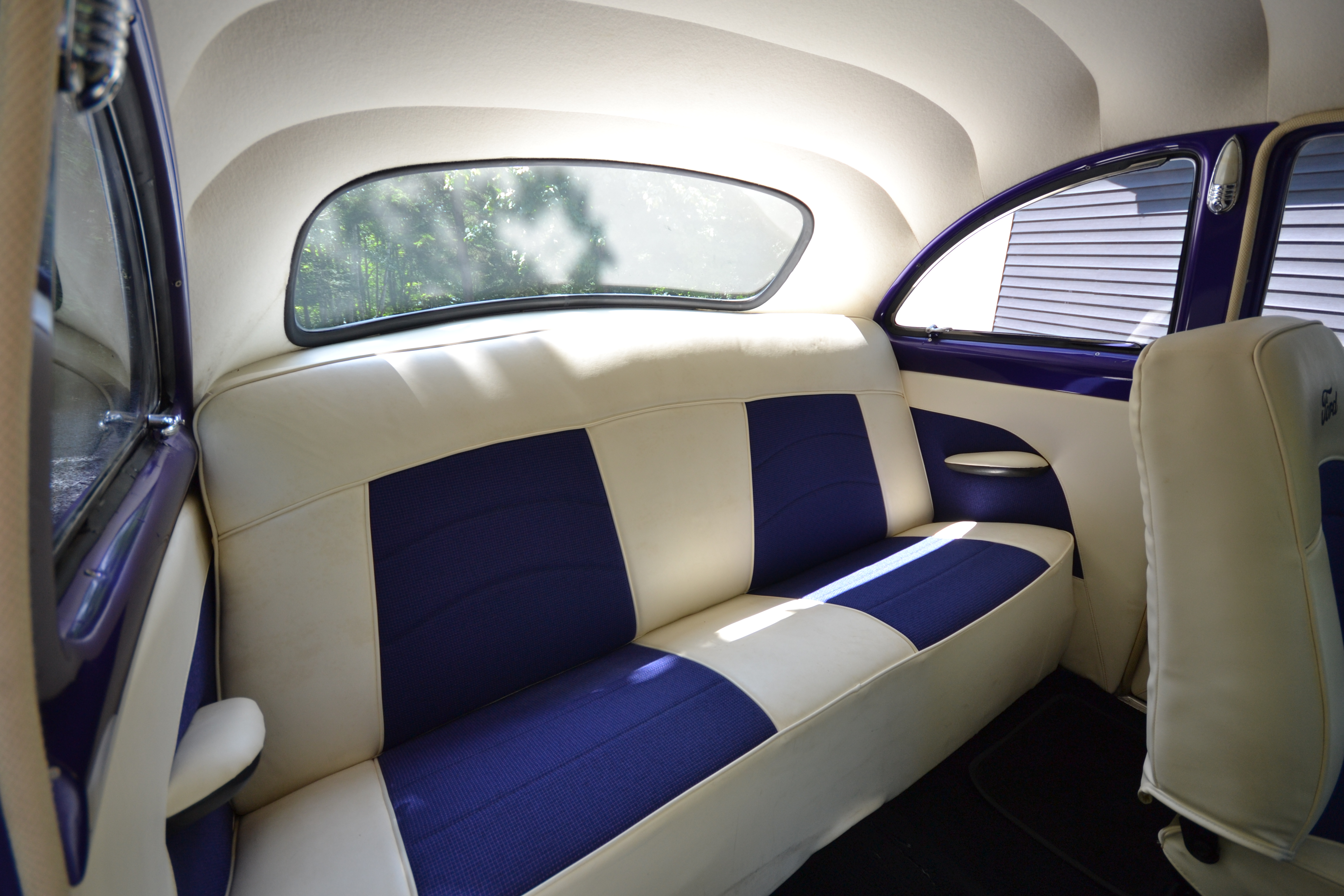 Beautiful refurnished interior of the purple 1950 Ford Coupe, featuring white and purple leather seats