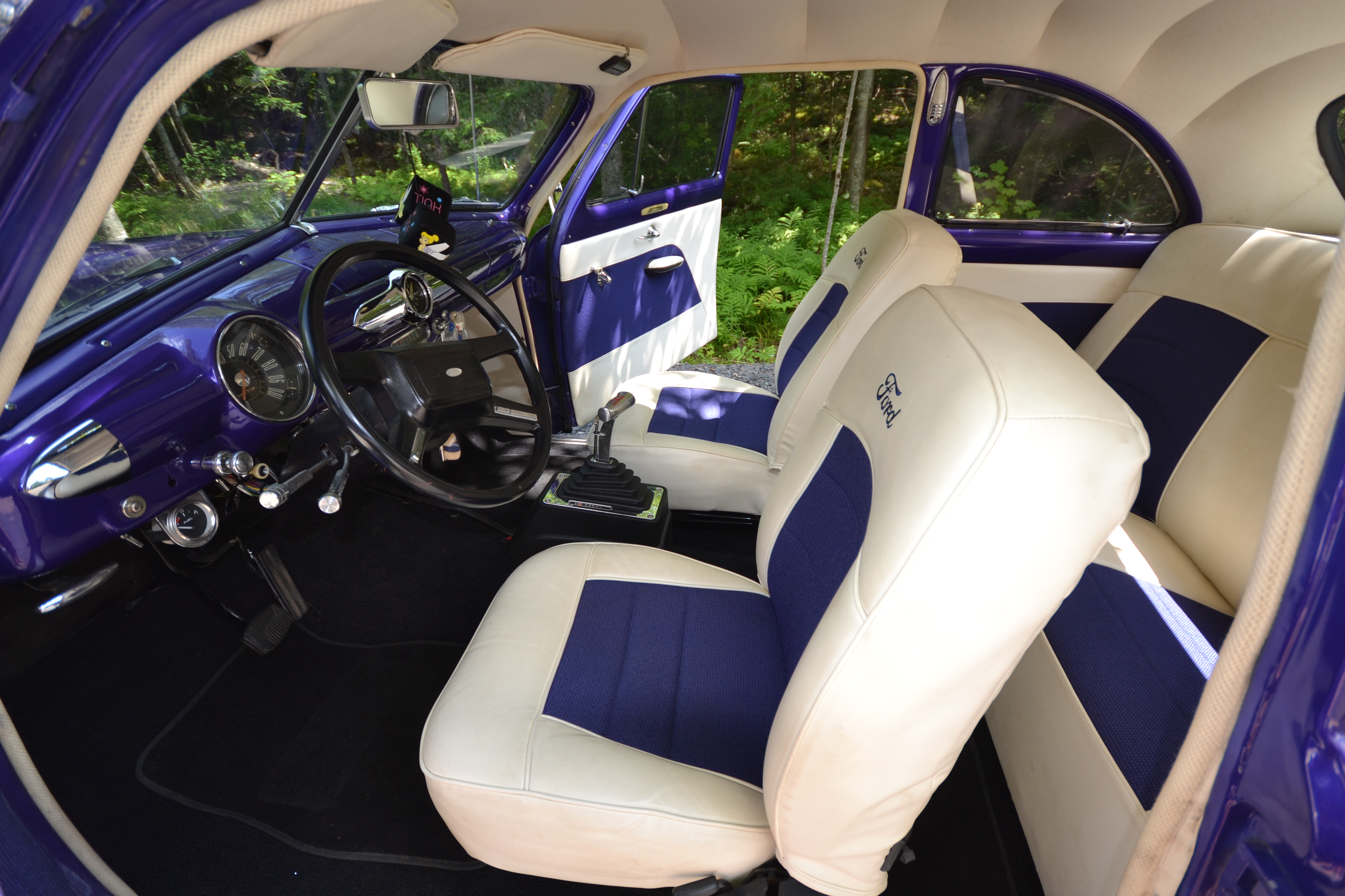  Beautiful refurnished interior of the purple 1950 Ford Coupe, featuring white and purple leather bucket seats